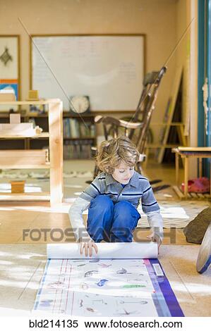 Boy rolling up poster in classroom View Large Photo Image Stock Photography - Boy rolling up poster in classroom. Fotosearch