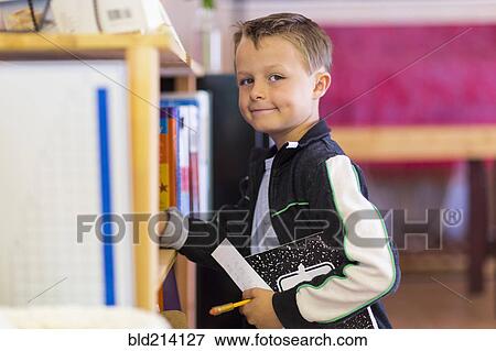Boy standing near shelf in classroom View Large Photo Image Stock Photo - Boy standing near shelf in classroom. Fotosearch