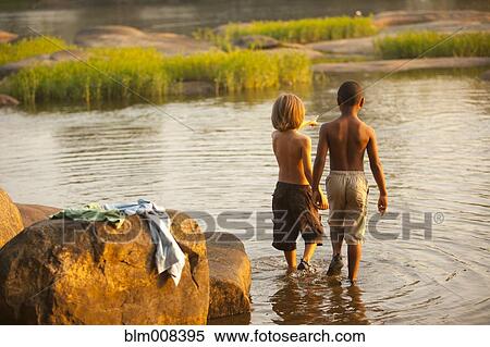 Stock Photography - Boys wading in lake together. Fotosearch