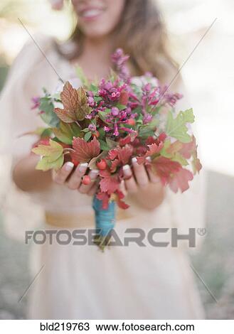 Stock Image - Bride holding bouquet of flowers. Fotosearch