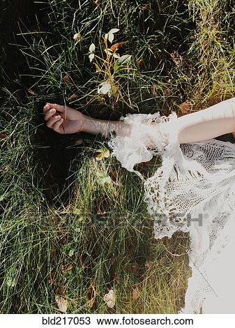 Stock Image - Bride wearing wedding dress in tall grass. Fotosearch