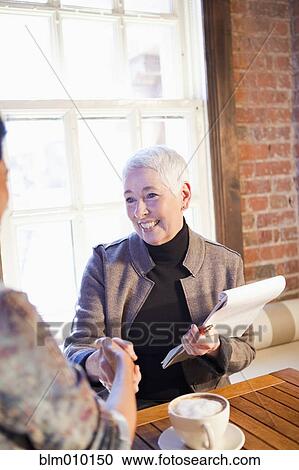 Stock Image - Business owner shaking hands with customer in cafe. Fotosearch
