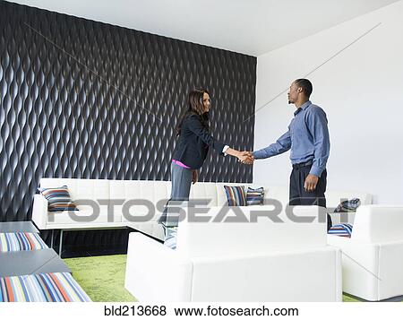 Stock Photo - Business people shaking hands in office lobby. Fotosearch