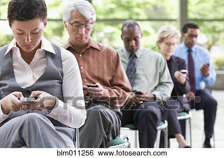 Business people sitting in chairs text messaging on cell phones View Large Photo Image Stock Photograph - Business people sitting in chairs text messaging on cell phones. Fotosearch