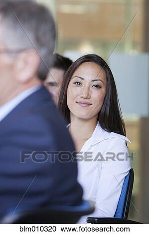 Stock Image - Business people sitting together in conference room. Fotosearch