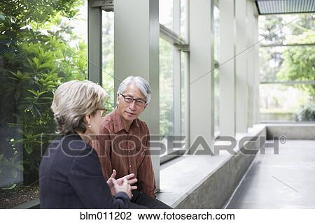Stock Image - Business people talking in lobby. Fotosearch