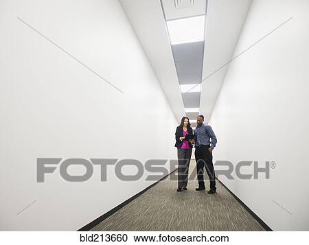 Stock Image - Business people talking in office corridor. Fotosearch