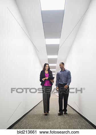Stock Image - Business people talking in office corridor. Fotosearch