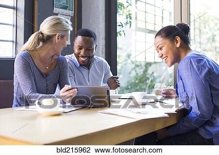 Stock Image - Business people using digital tablet in office meeting. Fotosearch