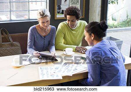 Stock Image - Business people using digital tablet in office meeting. Fotosearch