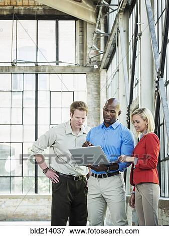 Stock Photo - Business people using laptop in warehouse. Fotosearch