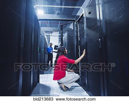 Stock Image - Business people working in server room. Fotosearch