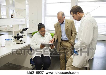 Stock Photo - Businessman and scientists using digital tablet in laboratory. Fotosearch