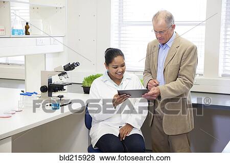 Stock Photo - Businessman and scientists using digital tablet in laboratory. Fotosearch