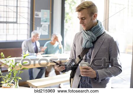 Stock Photo - Businessman using cell phone in office. Fotosearch