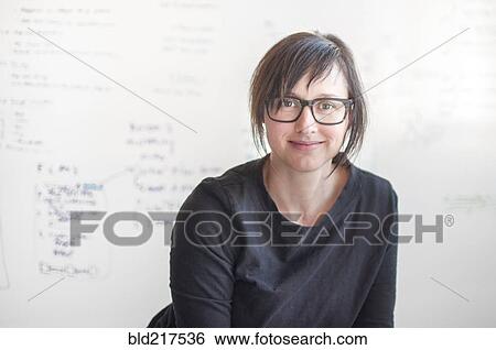 Stock Photograph - Businesswoman smiling near whiteboard in office. Fotosearch
