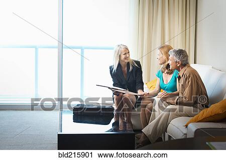 Businesswoman talking to couple on sofa View Large Photo Image Stock Image - Businesswoman talking to couple on sofa. Fotosearch