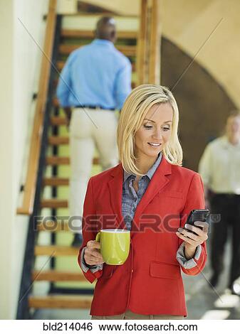 Stock Photograph - Businesswoman using cell phone near staircase. Fotosearch