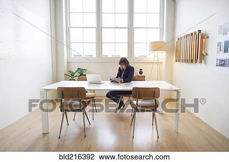 Stock Image - Businesswoman using digital tablet at desk in office. Fotosearch