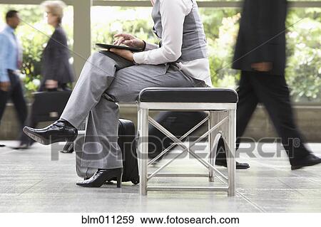 Stock Photo - Businesswoman using digital tablet in busy lobby. Fotosearch