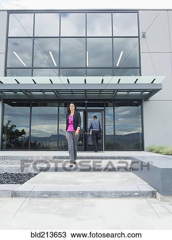Stock Image - Businesswoman walking outside office building. Fotosearch