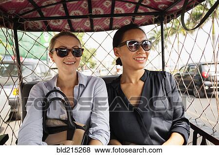 Stock Photo - Businesswomen riding in tuk tuk taxi. Fotosearch