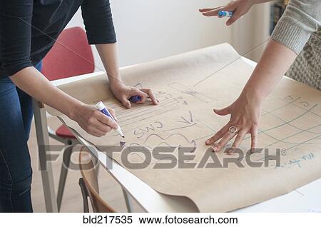 Stock Photography - Businesswomen sketching diagram in office. Fotosearch