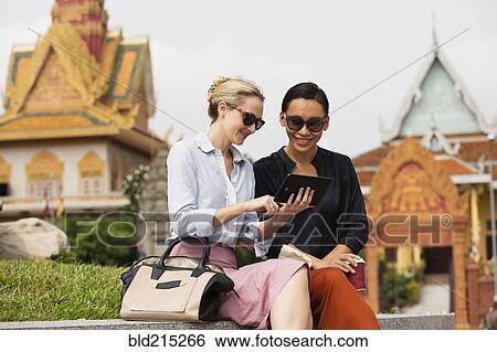 Businesswomen using digital tablet near temple, Phnom Penh, Cambodia View Large Photo Image Stock Photograph - Businesswomen using digital tablet near temple, Phnom Penh, Cambodia. Fotosearch