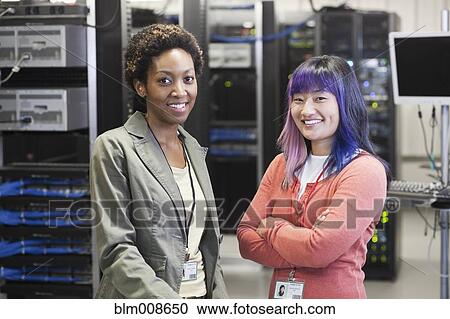 Stock Image - Businesswomen working in office technology room. Fotosearch