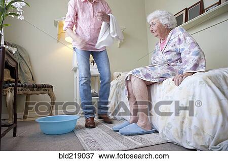 Caregiver helping older woman in bedroom View Large Photo Image Stock Photo - Caregiver helping older woman in bedroom. Fotosearch