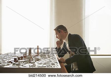 Stock Image - Caucasian architect examining urban model in office. Fotosearch