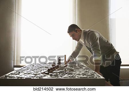 Stock Image - Caucasian architect examining urban model in office. Fotosearch