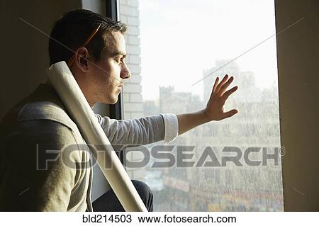 Stock Image - Caucasian architect looking out office window. Fotosearch