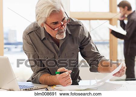 Caucasian architect working on papers in office View Large Photo Image Stock Image - Caucasian architect working on papers in office. Fotosearch