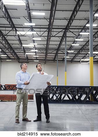 Caucasian architects reading blueprints in warehouse View Large Photo Image Stock Photography - Caucasian architects reading blueprints in warehouse. Fotosearch