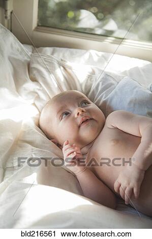 Stock Image - Caucasian baby laying on bed. Fotosearch