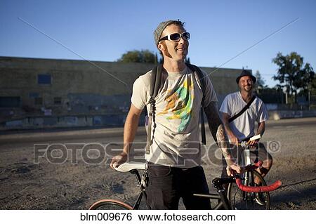 Caucasian bicycle messengers stopping on city street View Large Photo Image Stock Photograph - Caucasian bicycle messengers stopping on city street. Fotosearch