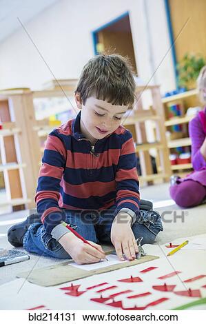 Stock Image - Caucasian boy drawing in classroom. Fotosearch