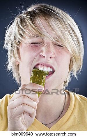 Stock Image - Caucasian boy eating pickle. Fotosearch