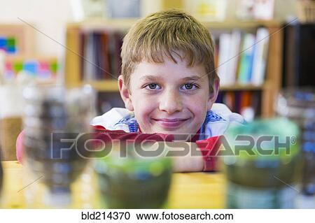 Stock Image - Caucasian boy leaning chin on desk in classroom. Fotosearch