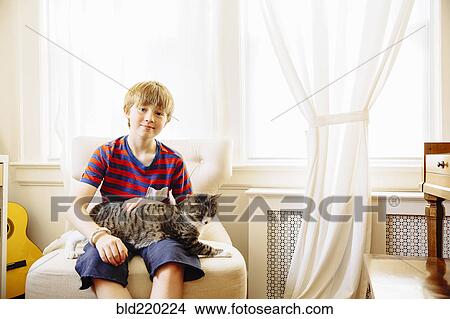 Caucasian boy petting cat in living room View Large Photo Image Picture - Caucasian boy petting cat in living room. Fotosearch