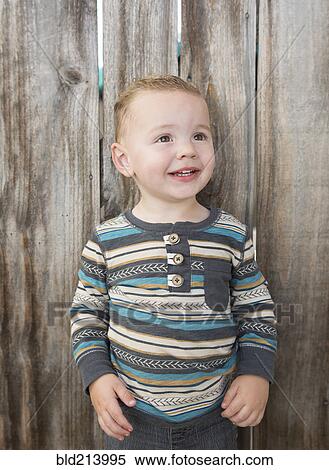 Caucasian boy smiling near wooden fence View Large Photo Image Stock Photography - Caucasian boy smiling near wooden fence. Fotosearch