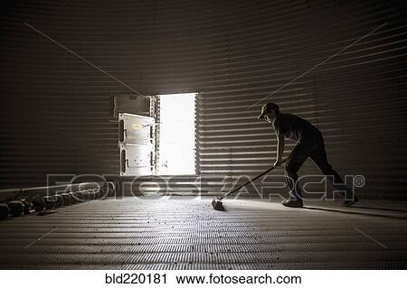 Stock Image - Caucasian boy sweeping empty silo. Fotosearch