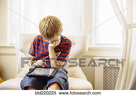Stock Photography - Caucasian boy using digital tablet in living room. Fotosearch