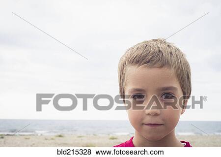Stock Photo - Caucasian boy with serious expression on beach. Fotosearch
