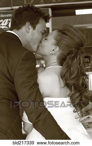 Stock Photo - Caucasian bride and groom kissing at reception. Fotosearch