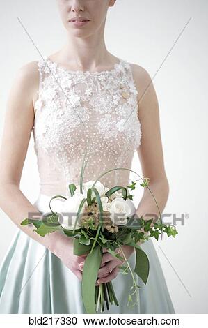 Stock Image - Caucasian bride in wedding dress holding bouquet. Fotosearch