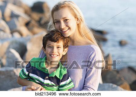 Stock Photograph - Caucasian brother and sister smiling on rocky beach. Fotosearch