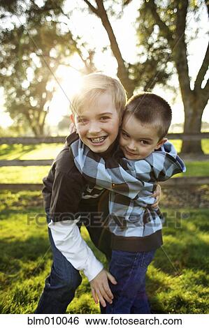 Stock Photograph - Caucasian brothers hugging outdoors. Fotosearch