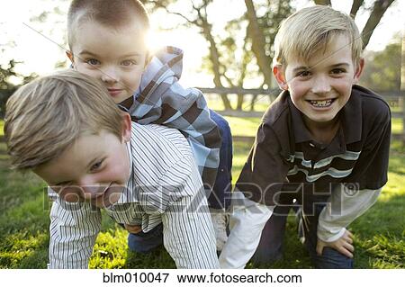 Stock Photo - Caucasian brothers playing in grass. Fotosearch